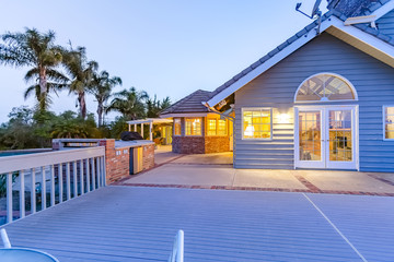 Large blue house with large deckfrom the backyard at twilight