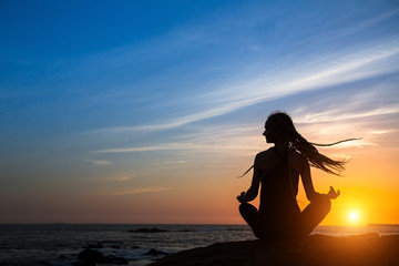 Meditation woman yoga silhouette. Fitness and healthy lifestyle, ocean during amazing sunset.