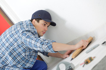 man removing masking tape from skirting board