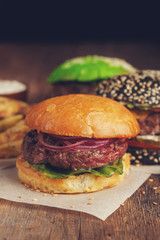 Closeup of set of three mini homemade Burger with marble beef and vegetables on a wooden Board