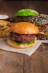 Closeup of set of three mini homemade Burger with marble beef and vegetables on a wooden Board