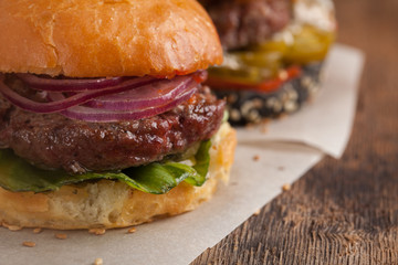 Closeup of set of three mini homemade Burger with marble beef and vegetables on a wooden Board
