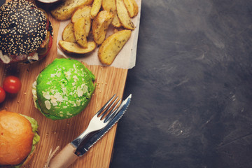 set of three mini homemade Burger with marble beef and vegetables on a wooden Board. the concept of junk food and fast food on dark concrete background. Top View with copy space