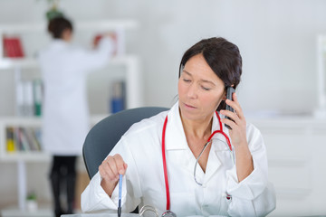 confident middle-aged female doctor talking on phone