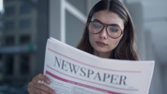 Young woman reading newspaper in outdoors
