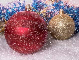 Christmas balls on the snow. Blurred background of fir-tree tinsel. Falling snow