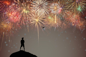 Fototapeta na wymiar Silhouette of photographer control the drone for taking photo of Multicolor Firework Celebration over the working space for text with bokeh background, Greeting and card celebration concept