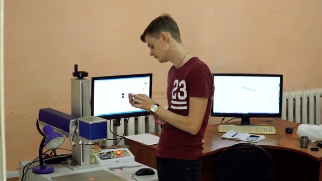CNC engrave. Laser engraving on metal. Worker monitors the CNC machine.