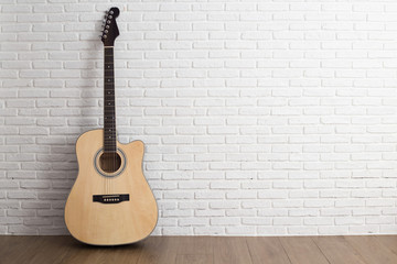 Acoustic guitar  over brick wall white background with copy space