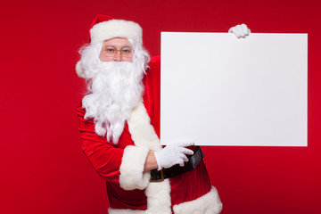 Naklejka premium Santa Claus pointing in blank advertisement banner isolated on red background with copy space