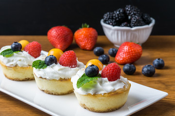Mini cheesecakes with Strawberry and whipped cream on a plate.