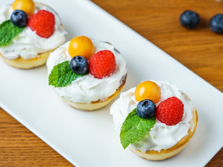 Mini cheesecakes with Strawberry and whipped cream on a plate.