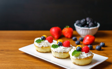 Mini cheesecakes with Strawberry and whipped cream on a plate.