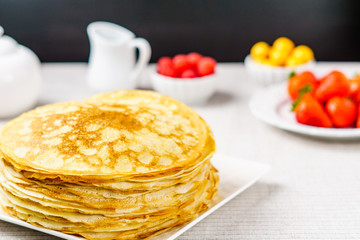 Pile of just made hot Russian pancakes or blini with berries.