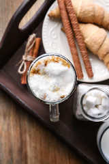 Glass with latte macchiato and tasty pastry on wooden tray