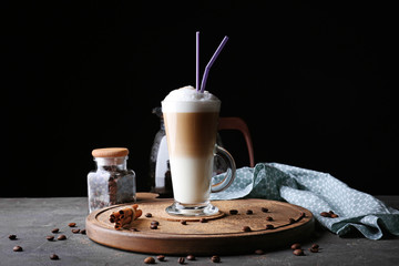 Glass with latte macchiato on table against black background