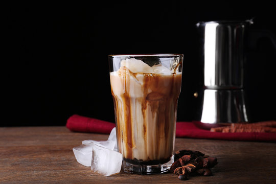 Glass with cold latte macchiato on table against black background