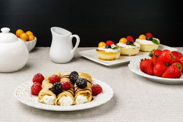 Crepes stuffed with cheese and berry topping on a plate for breakfast.