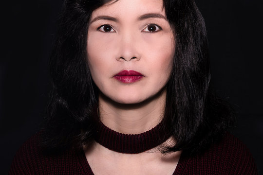 A close up portrait of an oriental woman on a black background