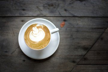 Low key of white cup of hot coffee with the white cream and white plate on the wooden table in the restaurant or coffee shop, cappuccino.
