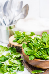 Lettuce leaves in a wooden bowl and on a table