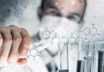 Young scientist mixing reagents in glass flask in clinical laboratory