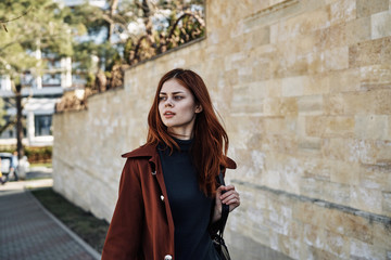 Beautiful young woman with red hair walking outdoors, city