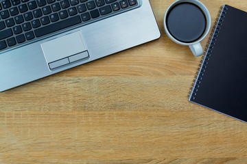 Laptop computer or notebook, note and cup of coffee on working table with copy space top view.