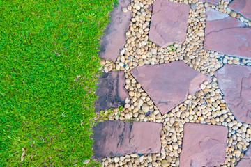 Green grass field with stone pathway and small rock decoration.