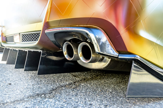Orange car with dual exhaust pipes on concrete