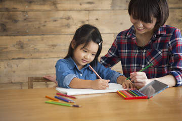 Japanese girl is drawing picture with colored pencil.