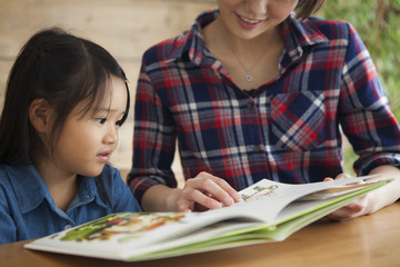 A young mother and a girl read a picture book together.