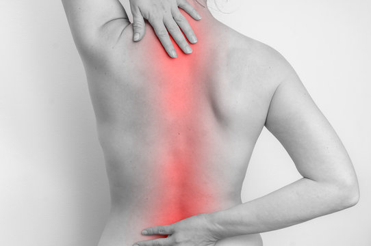 Woman with spine pain is holding her aching back