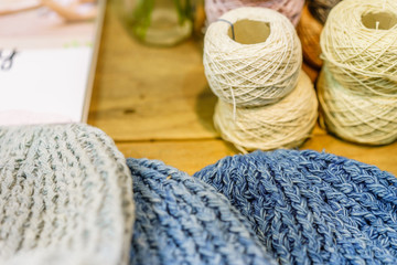Yarn for knitting, knitted color hat or cap on a wooden background. View from above. balls of yarn for knitting in different colors.