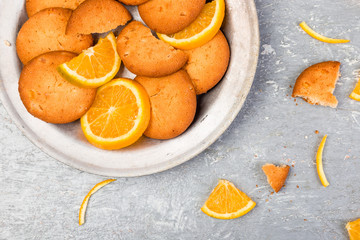 Cookies and orange citrus fruit on metal plate on grey background. Flat lay