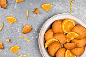 Cookies and orange citrus fruit on metal plate on grey background. Flat lay
