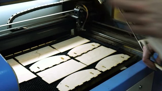 CNC engrave. Laser engraving on wood. Worker monitors the CNC machine.