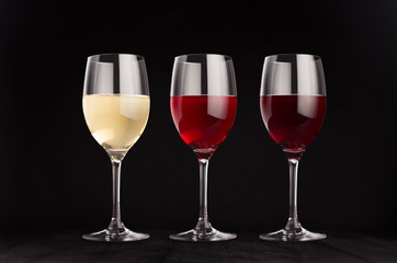 Wine glasses set with red, rose, white wine,  mock up on elegant dark black wooden background.