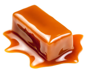Caramel sauce flowing on caramel candies, isolated on white background. Golden Butterscotch toffee candy caramels.
