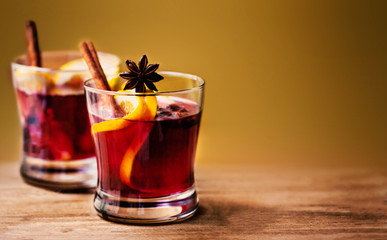Hot Mulled Wine for winter and Christmas  on wooden background with copyspace.  Red Hot wine with orange fruit, spices and Christmas Decorations. Traditional drink on winter holiday in rustic style.