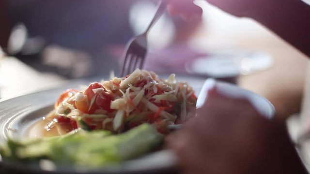 Close up of woman eats papaya salad, som tum, tum Thai, asia salad made of papaya and vegetables Thai Style served in the restaurant, 1920x1080.