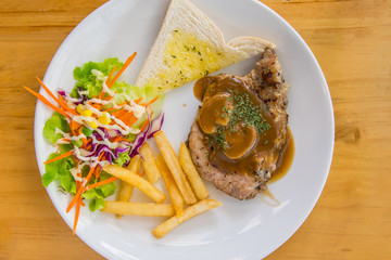 Pork chop steak with potato salad and toast on a white plate