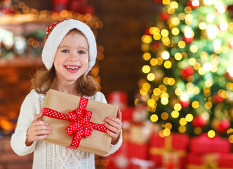 happy laughing child girl with christmas present at home