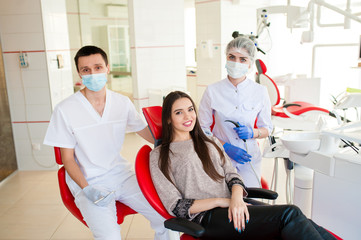 A dentist with an assistant, heals teeth to a beautiful girl.