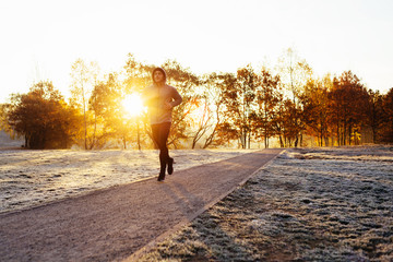 Athletic man running during cold winter, autumn morning