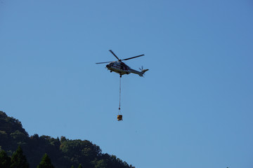 Fototapeta na wymiar 山で物資を運ぶヘリコプター