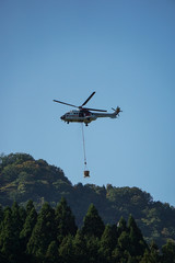 Fototapeta na wymiar 山で物資を運ぶヘリコプター
