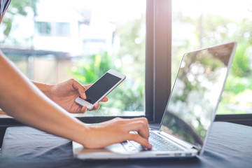 Business women hand use mobile phones and are working on a laptop computer in the office.
