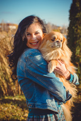 Pretty brunette hair young woman on a walk with friend little nice red dog pekingese. Lady of dog lover and pets. Dog owner with lovely pet