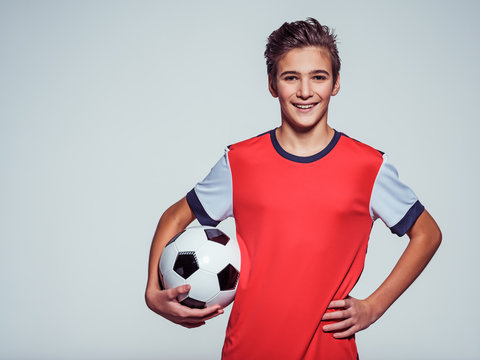 smiling teen boy in sportswear holding soccer ball